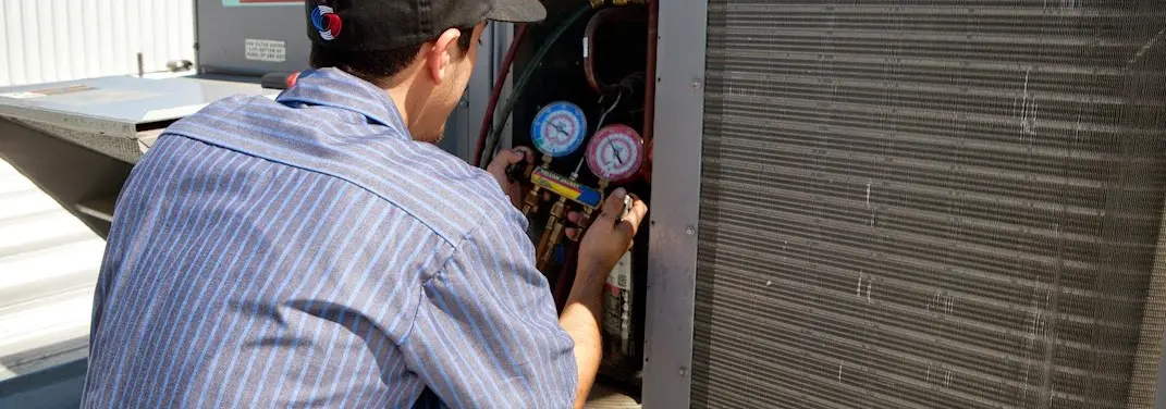 HVAC technician servicing a condenser unit in London